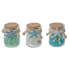 three glass jars with starfish and shells in them