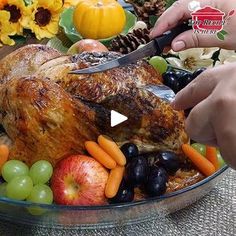 someone cutting into a turkey with fruit and vegetables