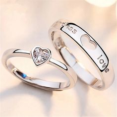 two wedding rings with hearts and names engraved on the sides, one is white gold