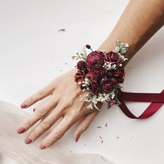 a woman's hand wearing a red wrist corsage