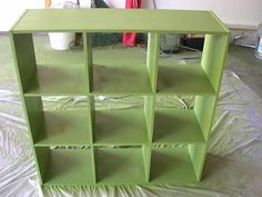 a green bookcase sitting on top of a plastic sheet covered floor next to a wall