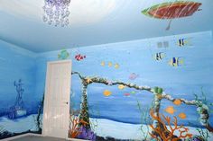 a room with blue walls and an underwater scene painted on the wall next to a white door