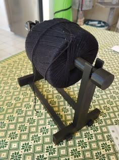 a ball of yarn sitting on top of a black stand next to a green and white tile floor