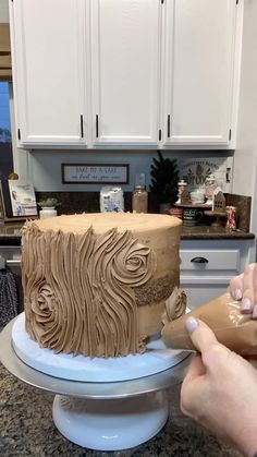 a person is decorating a cake with icing on a table in a kitchen