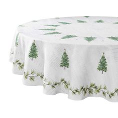 a white table cloth with green trees on it and snowflakes around the edges