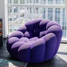 a purple chair sitting on top of a wooden floor in front of a large window