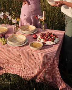 a man and woman standing next to a table with food on it