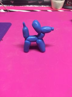 a small blue toy sitting on top of a pink table