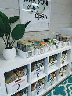 a white book shelf filled with books next to a potted plant