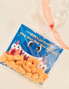 a bag filled with dog treats sitting on top of a white table next to a ribbon