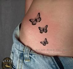 a woman's stomach with three butterflies tattoo on the side of her belly,