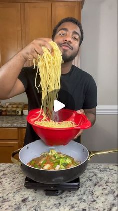 a man is eating noodles from a red bowl