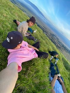 two people laying on the grass with their feet in the air and one person wearing a hat