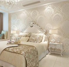 a large white bed sitting in a bedroom next to a window with a chandelier