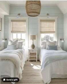 two beds in a bedroom with white linens and pillows on them, one has a wicker basket hanging from the ceiling