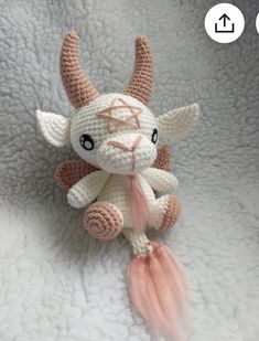 a crocheted stuffed animal with an orange tail on a white blanket, it looks like a demon