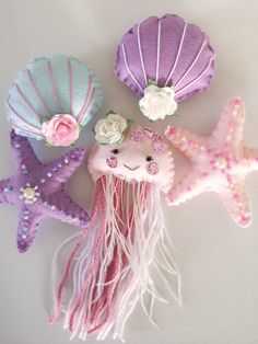 three little stuffed animals that are next to each other on a white surface with pink, purple and blue colors