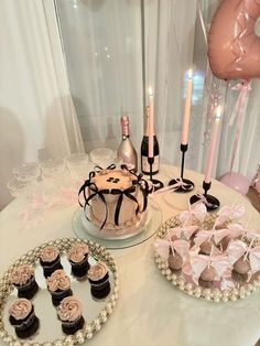 a table topped with cakes and cupcakes on top of a white table cloth