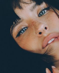 a woman with freckled hair and blue eyes is posing for the camera while holding her hand up to her face