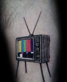 an old tv tattoo on the left thigh with color bars coming out of it,