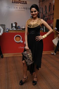 a woman in a black dress holding a leopard print purse and posing for the camera