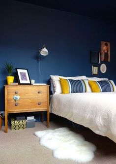 a bed room with a neatly made bed next to a night stand and a dresser