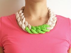 a woman wearing a pink shirt with a green and white crochet necklace on her neck