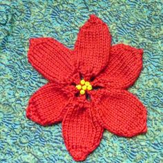 a red knitted flower laying on top of a blue blanket