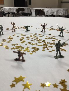 small toy soldiers are arranged in the shape of stars on a table with white linens