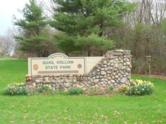 the sign for quail hollow state park is in front of some flowers and trees