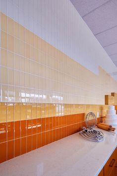 a kitchen with orange and white tiles on the wall, counter top and stovetop