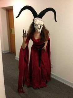 a woman in a red dress and goat mask