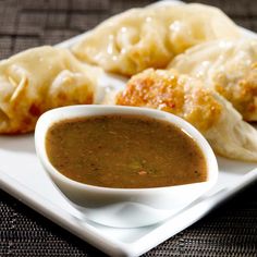 a white plate topped with dumplings and dipping sauce