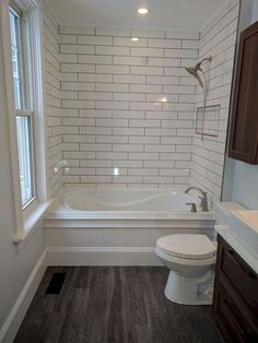 a white toilet sitting next to a bath tub in a bathroom with wooden floors and walls