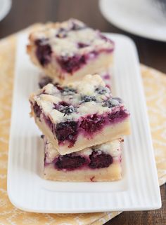 three pieces of blueberry cheesecake sitting on a white plate next to each other