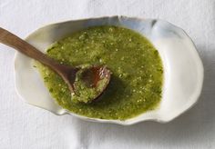 a wooden spoon in a white bowl filled with pesto