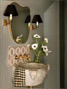 a sink and mirror in a room with wall paper on the walls next to it