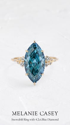 a blue diamond ring with two diamonds on top and the words melanie casey above it