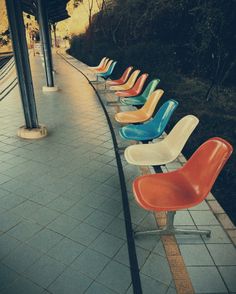 a row of colorful chairs sitting on top of a sidewalk