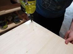 a person is working on a piece of wood with a power drill and screwdriver