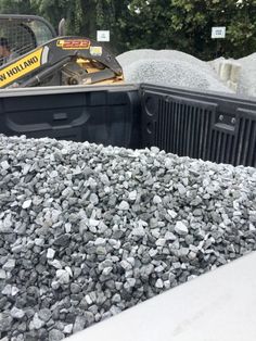 there is a large pile of rocks in the back of a truck with a bulldozer behind it