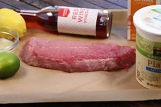 raw meat, yogurt, and other ingredients on a cutting board next to lemons