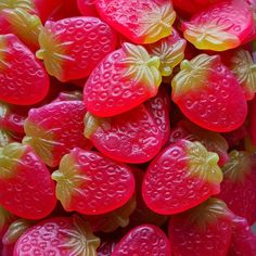 some very pretty red and yellow candies in the shape of strawberries with water droplets on them