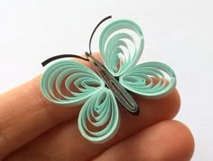 a hand holding a small butterfly brooch in it's left side, with the wings folded back