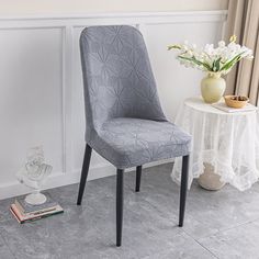 a blue chair next to a white table with flowers on it and a book near by