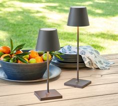 two lamps are sitting on a table with plates and fruit