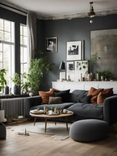 a living room filled with lots of furniture and plants on the wall above it's windows