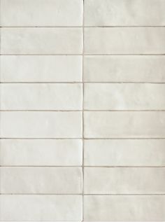 a white tile wall with vertical lines on the bottom, and horizontal stripes on the top