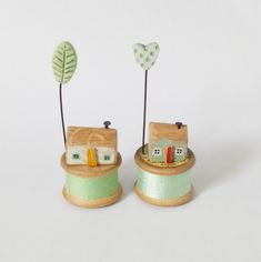 two small wooden houses sitting on top of a spool of thread next to each other