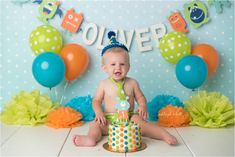 a baby is sitting on the floor in front of balloons and cake for his first birthday